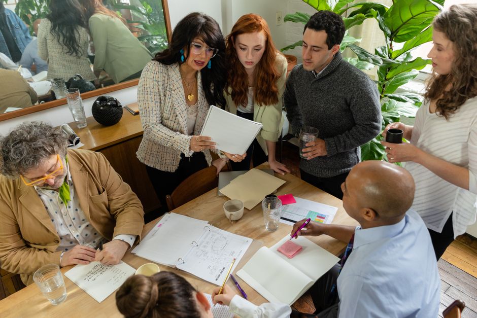 A diverse team discusses documents around a table in a modern office setting, promoting teamwork and collaboration.